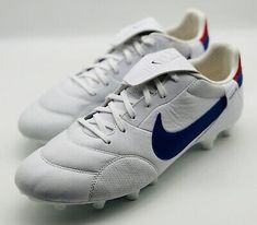 a pair of white and blue nike soccer shoes on a white surface with the word nike written