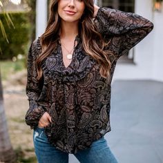 a woman posing in front of a house with her hands on her head and wearing jeans