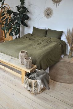 a bed sitting on top of a wooden floor next to a plant