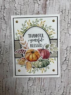 a thanksgiving card with pumpkins and leaves on it, sitting on a wooden surface