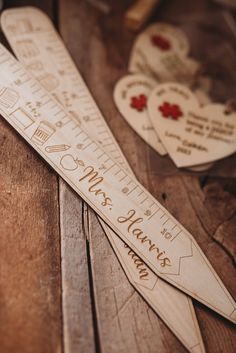 personalized wooden rulers with names and date engraved on them sitting on a table next to hearts