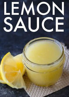 a glass jar filled with lemon sauce sitting on top of a napkin next to a sliced lemon