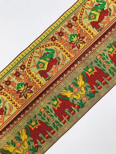 an intricately designed red and yellow ribbon on a white background with green, orange, and gold designs