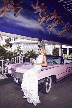 a woman sitting on top of a pink car