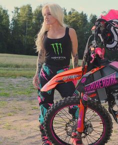 a woman standing next to a dirt bike