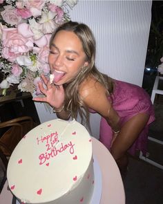 a woman is blowing out the candles on her birthday cake with pink flowers in the background