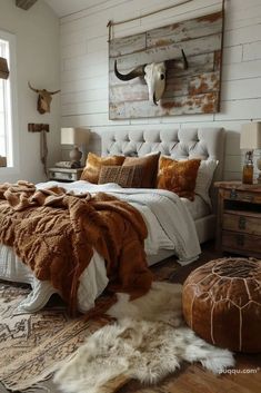 a bedroom with a bed, rugs and cow skull on the wall above it