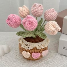 small crocheted flowers in a pot on a table next to a white box