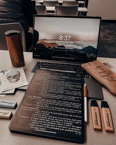 an open laptop computer sitting on top of a table next to some pens and pencils