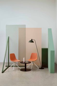 two chairs and a table in front of a wall with geometric designs on it,