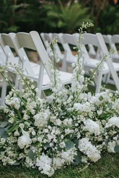 a bunch of white chairs sitting in the grass