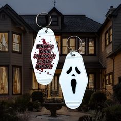 two keychains with faces on them in front of a house that says, what's your favorite scary movie?