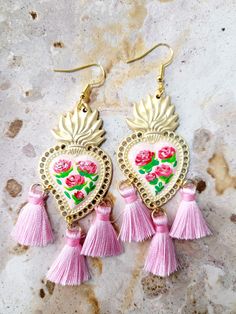 Beautiful handmade earrings delicately painted with a brush, on a light pink base and adorned with small hot pink roses and green leaves, adorned with light pink tassels, with several protective layers of jewelry varnish to protect the paint, quality and durability of the earrings. These earrings are inspired by Frida Khalo and hand painted with beautiful roses, part of our Mexican culture, they are the ideal accessory for any occasion, they will surely enhance your beauty since they are unique handcrafted pieces, the ideal gift for weddings, holidays or simply to make whoever gets it feel special, for its unique beauty. Features/ Product info Note: These earrings come in two sizes, large and small, please see attached photos. Size: Large The Main Material: Brass Color: Black and white - E Pink Bohemian Hand Painted Jewelry, Pink Hand Painted Heart Jewelry, Bohemian Pink Hand Painted Earrings, Bohemian Nickel-free Earrings For Valentine's Day, Pink Bohemian Jewelry For Valentine's Day, Bohemian Pink Jewelry For Valentine's Day, Handmade Bohemian Dangle Heart Earrings, Artisan Pink Earrings For Festival, Hand Painted Drop Earrings For Festivals