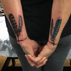 two people holding hands with tattoos on their arms and one has an arrow in the middle