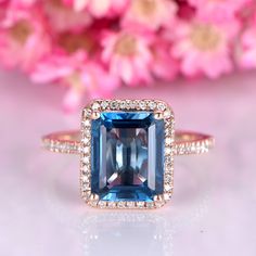 an engagement ring with a blue topazte surrounded by white diamonds and pink flowers