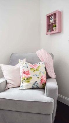 a gray chair with pink and white pillows