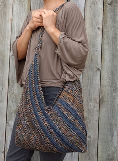 a woman is holding a large handbag in front of a wooden fence