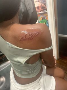 the back of a woman's shoulder with a tattoo on her left arm and chest