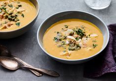 two bowls of soup with spoons next to each other on a gray counter top