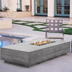 an outdoor fire pit sitting on top of a cement slab next to a swimming pool