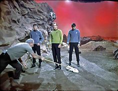 four men in star trek uniforms are cleaning the ground with a mop and shovel