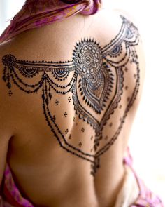 the back of a woman's body with hendi tattoos on her upper half