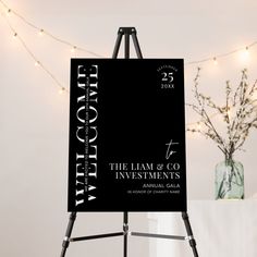 a black and white sign sitting on top of a easel next to a vase filled with flowers