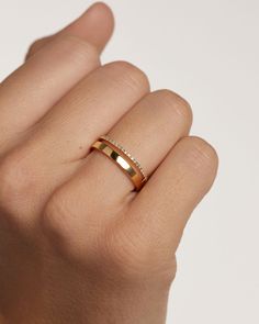 a woman's hand wearing a gold ring with two diamonds on the middle finger