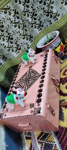 two small figurines sitting on top of a piece of pink luggage next to a rug