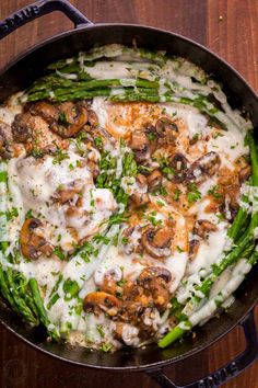 asparagus, mushrooms and cream sauce in a skillet on a wooden table