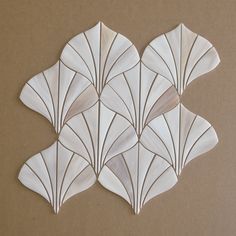 four white scallop shaped tiles sitting on top of a brown surface with lines drawn across them