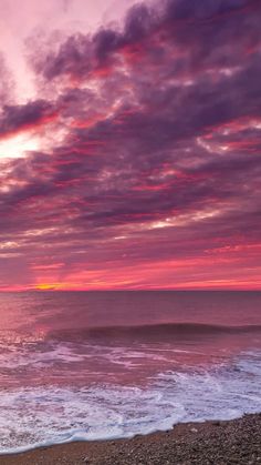 the sun is setting over the ocean with pink clouds