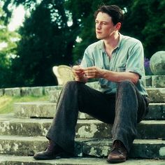 a man sitting on some steps with his feet up and looking at something in his hand