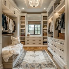 a walk - in closet with white cabinets and drawers, an area rug on the floor