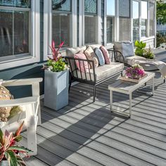 a porch with couches, tables and potted plants on the side of it