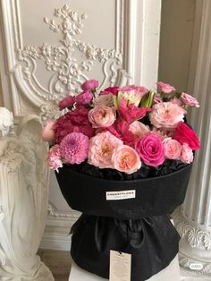 a bouquet of pink and red flowers in a black hat with a price tag on it