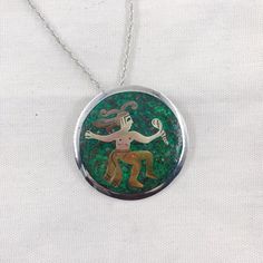 This vintage Mexican Silver piece functions as both a pendant and a brooch.  The piece features a green background with married metal overlay to create a figure in traditional dress.  This pendant comes with a 24" sterling silver wheat chain and is in good vintage condition.Stamps: Metales casadas (married metals) Mexico 925 Sterling Taxco Diameter: 68 mm/2 1/8 inchChain: 24 inch wheat styleThese pieces are pre-owned vintage jewelry. As this jewelry is not new there may be signs of wear or age. Green Sterling Silver Brooch Jewelry, Green Sterling Silver Brooch, Sterling Silver Green Brooch, Traditional Green Brooch Jewelry, Green Engraved Necklace For Collectors, Green Medallion Jewelry With Large Pendant, Green Medallion Pendant Jewelry, Green Sterling Silver Medallion Jewelry, Green Medallion Sterling Silver Jewelry