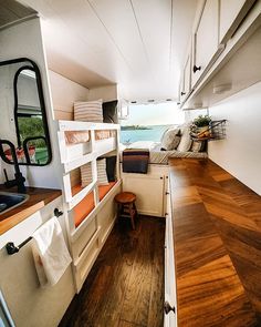 the interior of an rv with wood flooring and white walls, including bunk beds