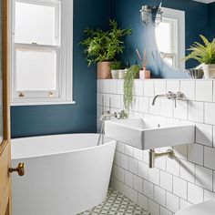 a white bath tub sitting under a bathroom window next to a toilet and sink in a bathroom