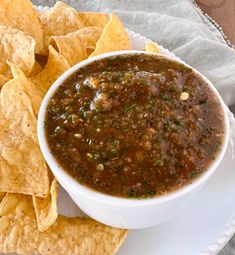 a white plate topped with a bowl of salsa and tortilla chips