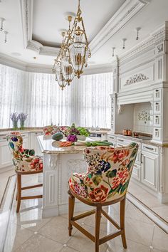 a chandelier hangs from the ceiling above a kitchen island with floral upholstered chairs