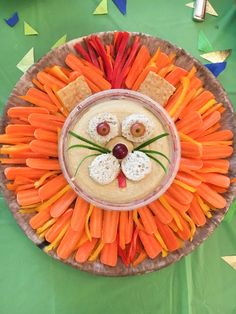 a plate with carrots and crackers in the shape of a lion's face