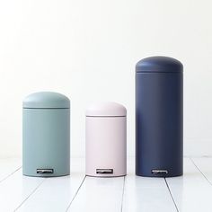 three different colored trash cans sitting on the floor