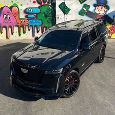 the black suv is parked in front of graffiti