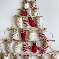 a christmas tree made out of knitted stockings and mittens hanging from a branch