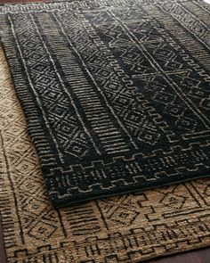 a black and beige rug on top of a wooden floor