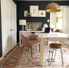 a desk with two chairs and a laptop on it in a room that has blue walls