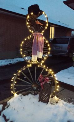 a snowman made out of an old fashioned wheel with lights on it's sides