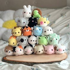 a pile of small crocheted animals sitting on top of a wooden board in front of a bed