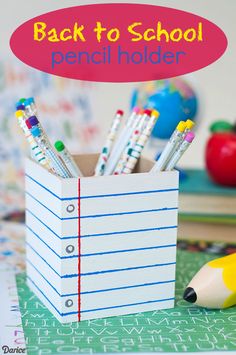 there are pencils and markers in a box on the table next to other school supplies